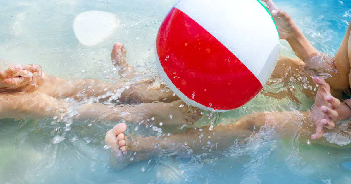 Kids playing at outdoor swimming pool. Little girl and boy play and swim in a home inflated pool .Water toys for children. Concept for summer vacations, relaxation and fun in the sunshine