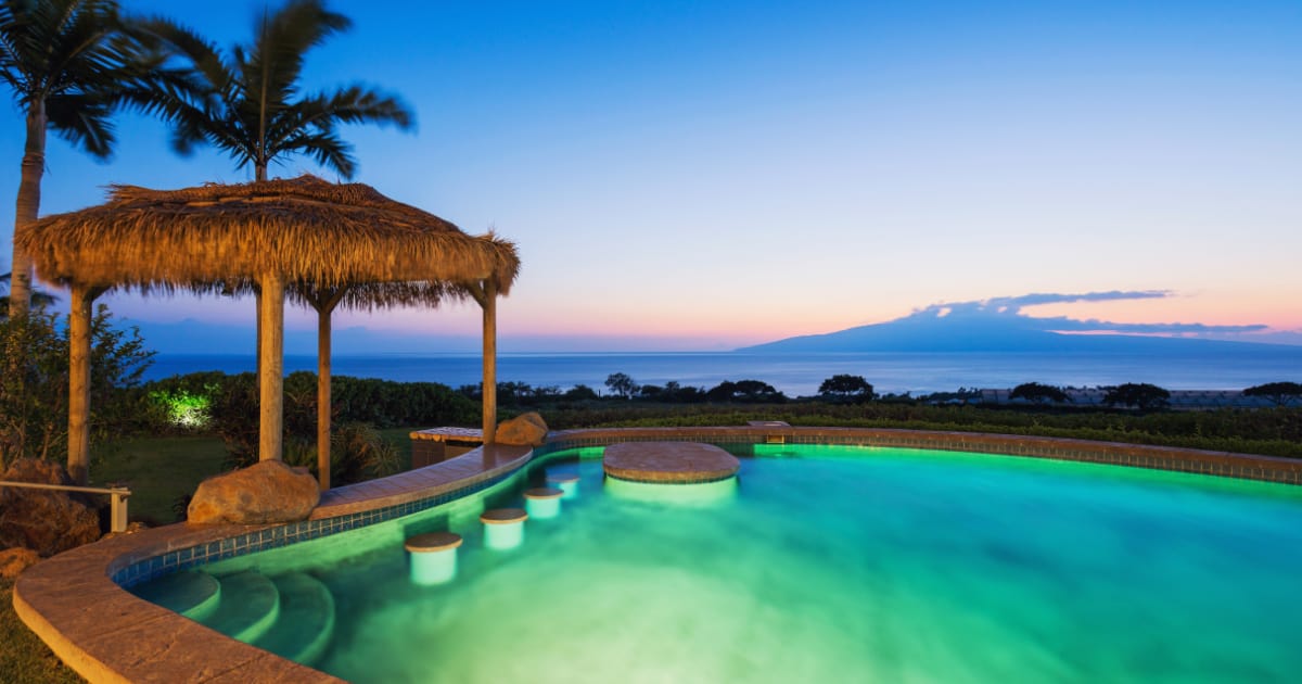 Luxury home with swimming pool lit up at sunset.